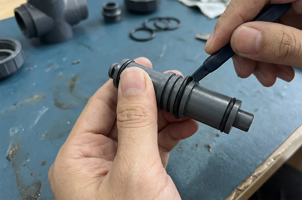 Trục van đã tháo rời với gioăng O-ring cũ đang được lấy ra khỏi rãnh bằng dụng cụ nạy nhựa